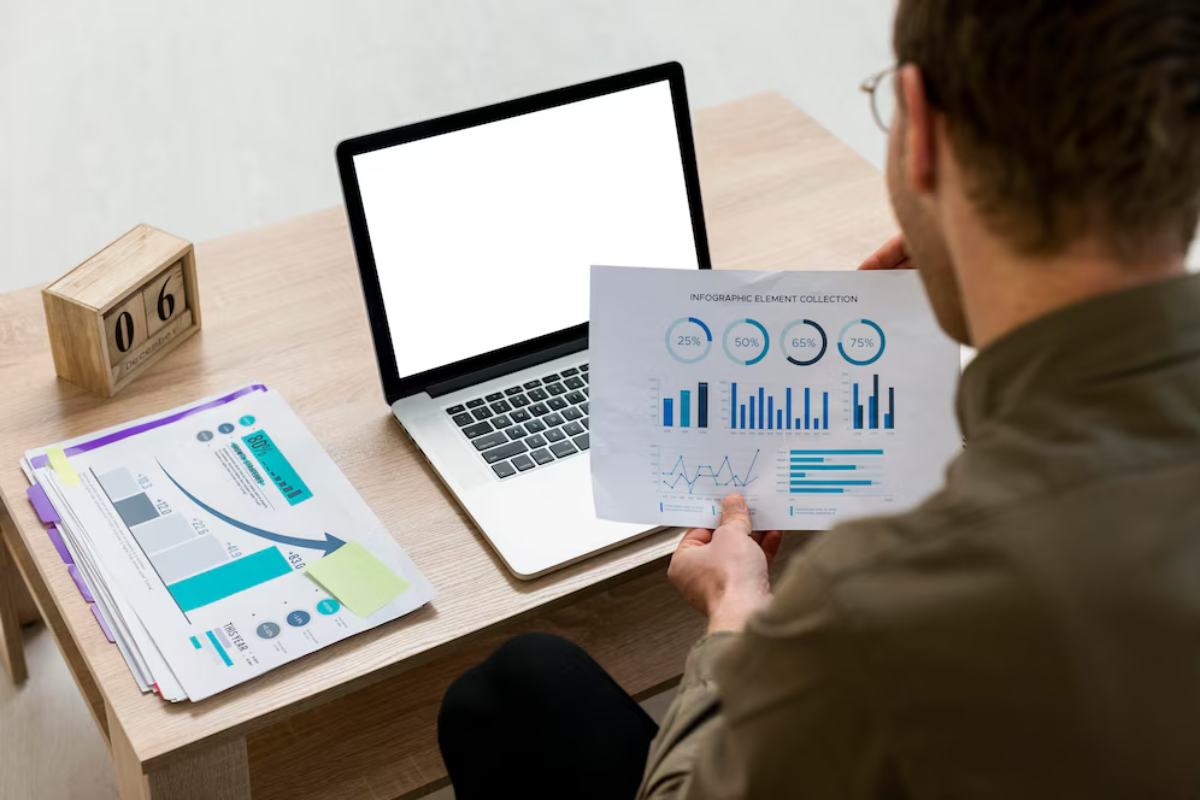 A person analyzes infographic data on paper while seated at a desk