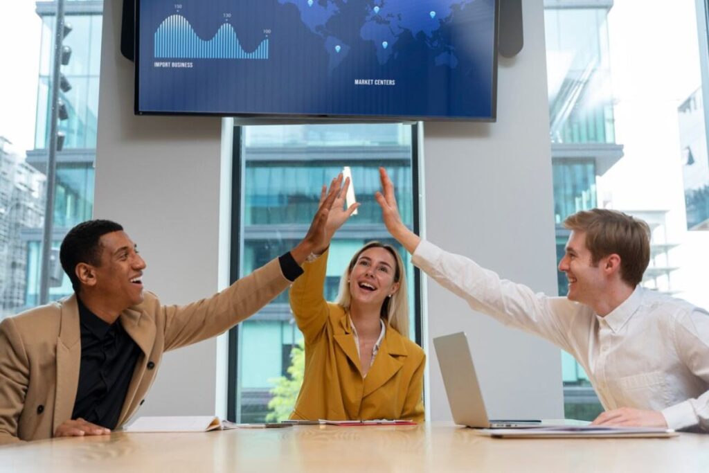 A diverse group of three people enthusiastically high-five each