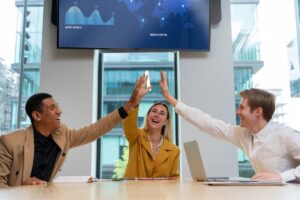A diverse group of three people enthusiastically high-five each