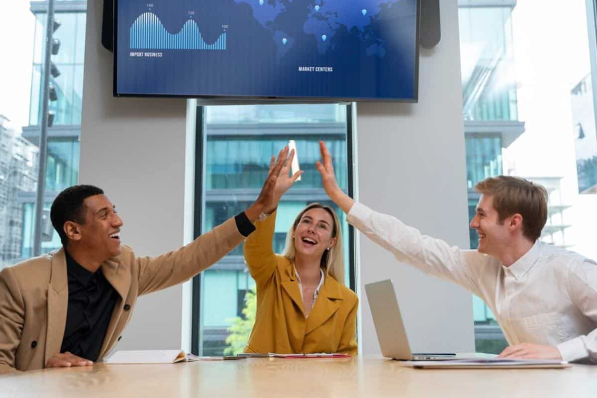 A diverse group of three people enthusiastically high-five each