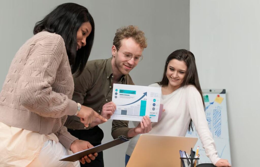 A group of three professionals review a report with charts and data