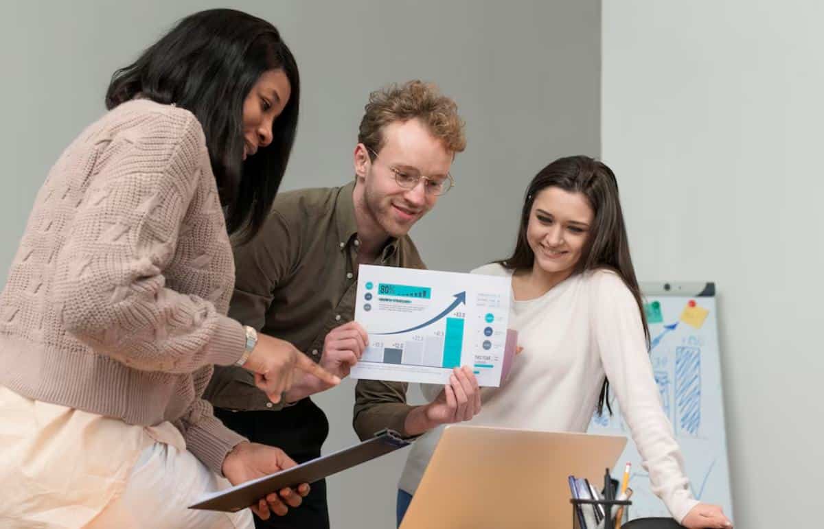 A group of three professionals review a report with charts and data